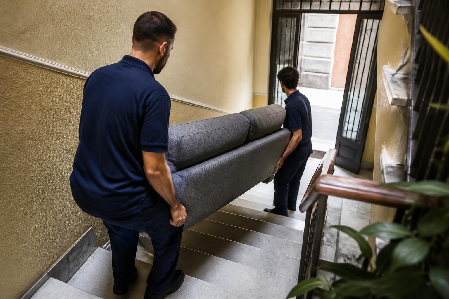 Dos transportistas bajando un sofá por las escaleras de un edificio en Madrid